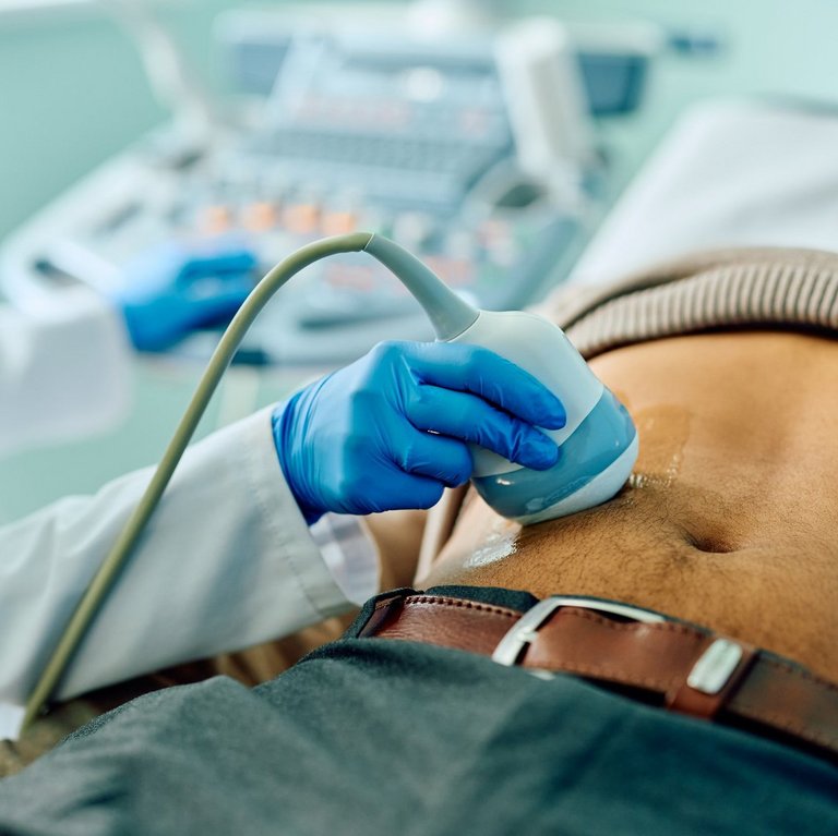 Ein Arzt macht einen Ultraschall am Bauch eines männlichen Patienten.
