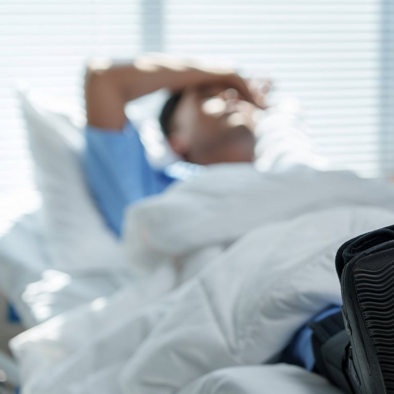 Eine medizinische Fachkraft im AKH Celle justiert eine Infusion. Im Hintergrund ist eine verschwommene Person zu erkennen.