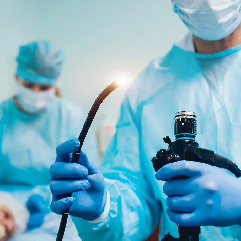 Arzt bereitet eine Endoskopie vor, während ein älterer Patient im Hintergrund für den Eingriff vorbereitet wird – moderne Diagnostik im Pankreaszentrum