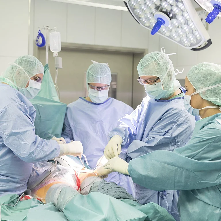 Operationsteam in steriler Kleidung führt Eingriff in einem hochmodernen OP-Saal durch.