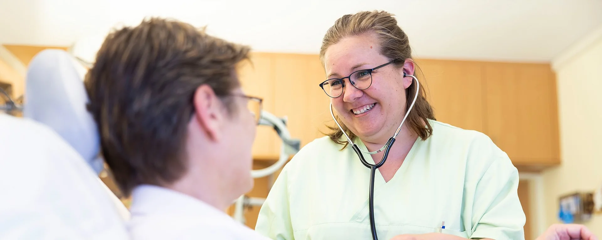 Eine Pflegekraft misst einer Patientin den Blutdruck – einfühlsam und mit einem Lächeln.