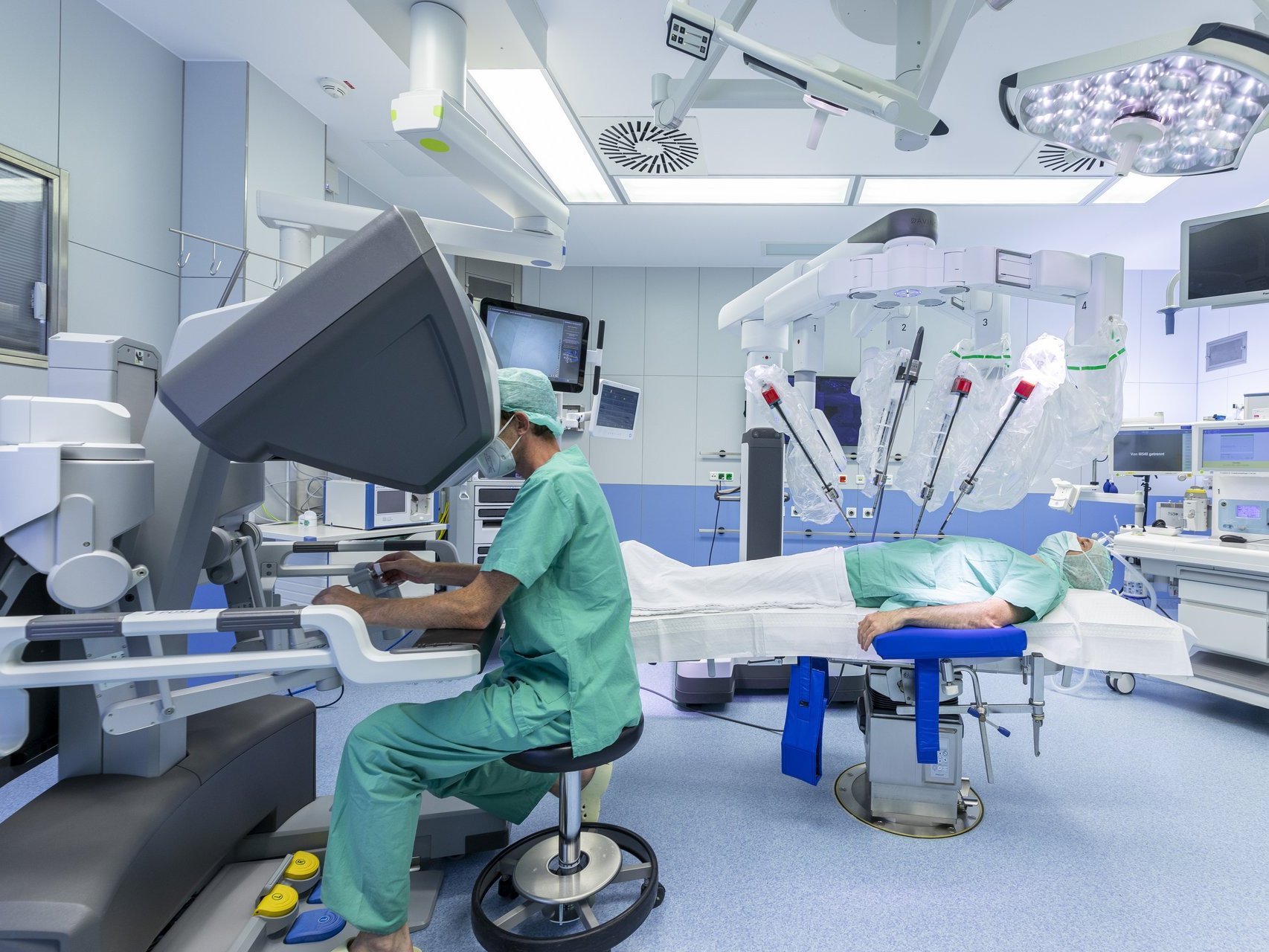 Chirurg steuert am AKH Celle einen Da-Vinci-Operationsroboter für eine minimalinvasive Operation, während der Patient im OP-Saal vorbereitet liegt.