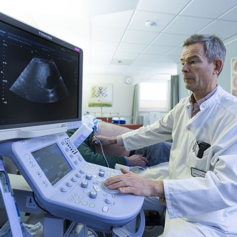 Ein Arzt macht einen Ultraschall an einem männlichen Patienten.