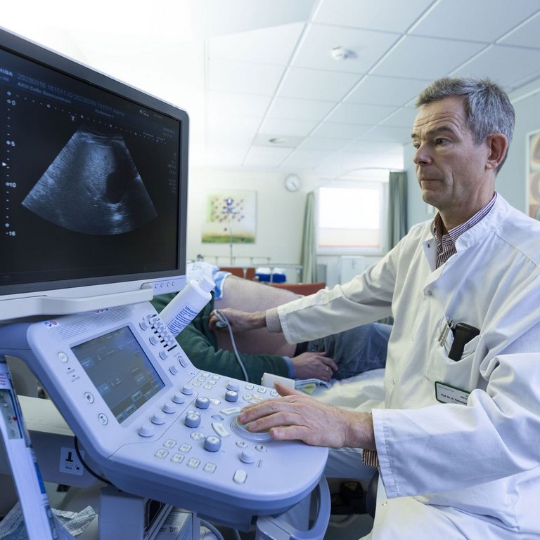 Ein Arzt macht einen Ultraschall an einem männlichen Patienten.