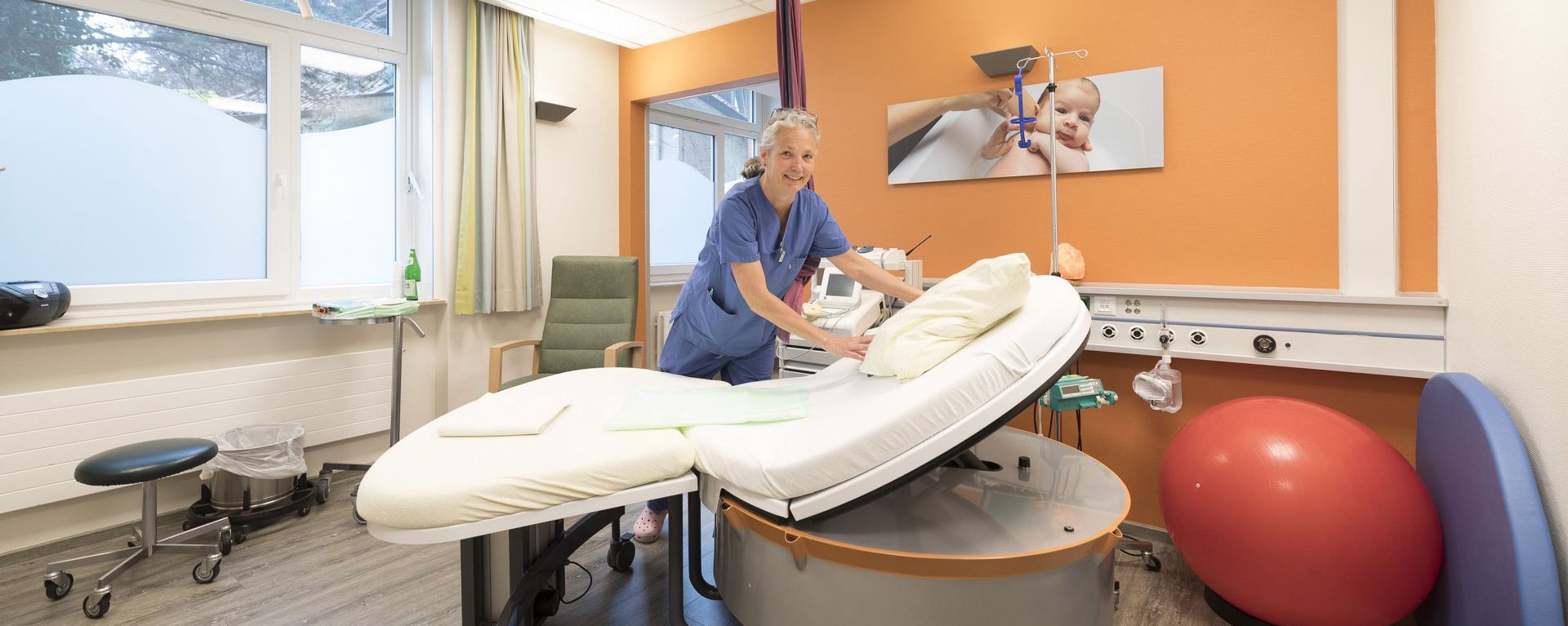 Geburtshelferin richtet das Bett in einem modernen Kreißsaal her.