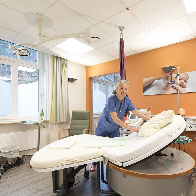 Geburtshelferin richtet das Bett in einem modernen Kreißsaal her.