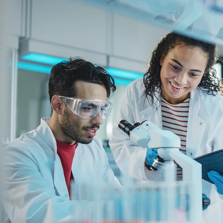 Junge Forschende im Labor analysieren Proben mit Mikroskop und Tablet