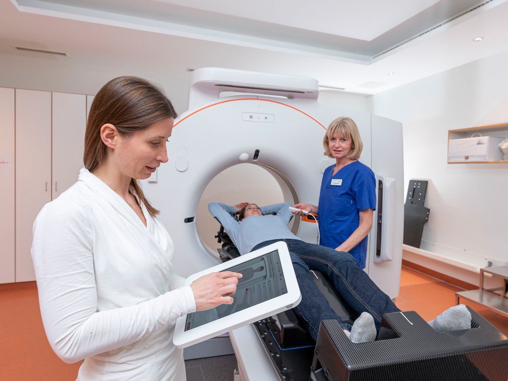 Patient wird im AKH Celle von medizinischem Fachpersonal in ein modernes Siemens-CT-Gerät eingeführt, gesteuert über ein Tablet.