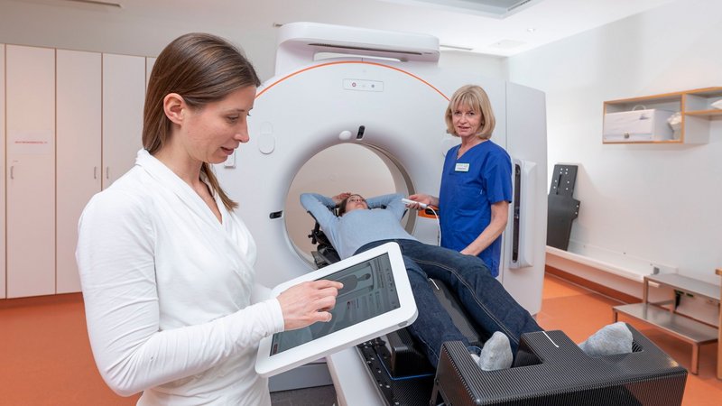 Patient wird im AKH Celle von medizinischem Fachpersonal in ein modernes Siemens-CT-Gerät eingeführt, gesteuert über ein Tablet.