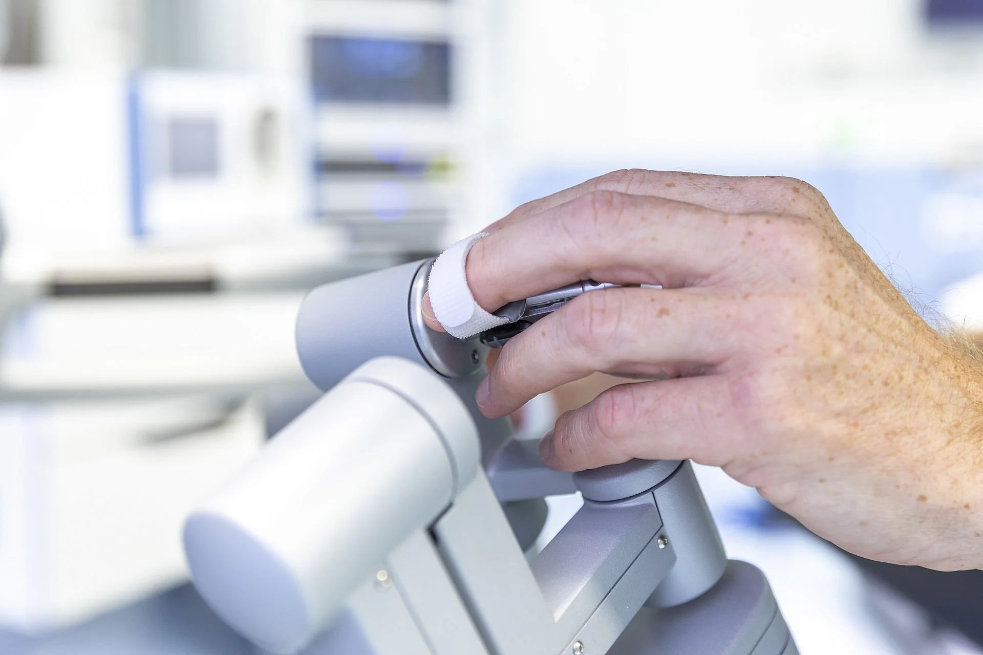 Nahaufnahme einer Hand, die ein Steuerungselement eines chirurgischen Robotersystems im Operationssaal bedient.