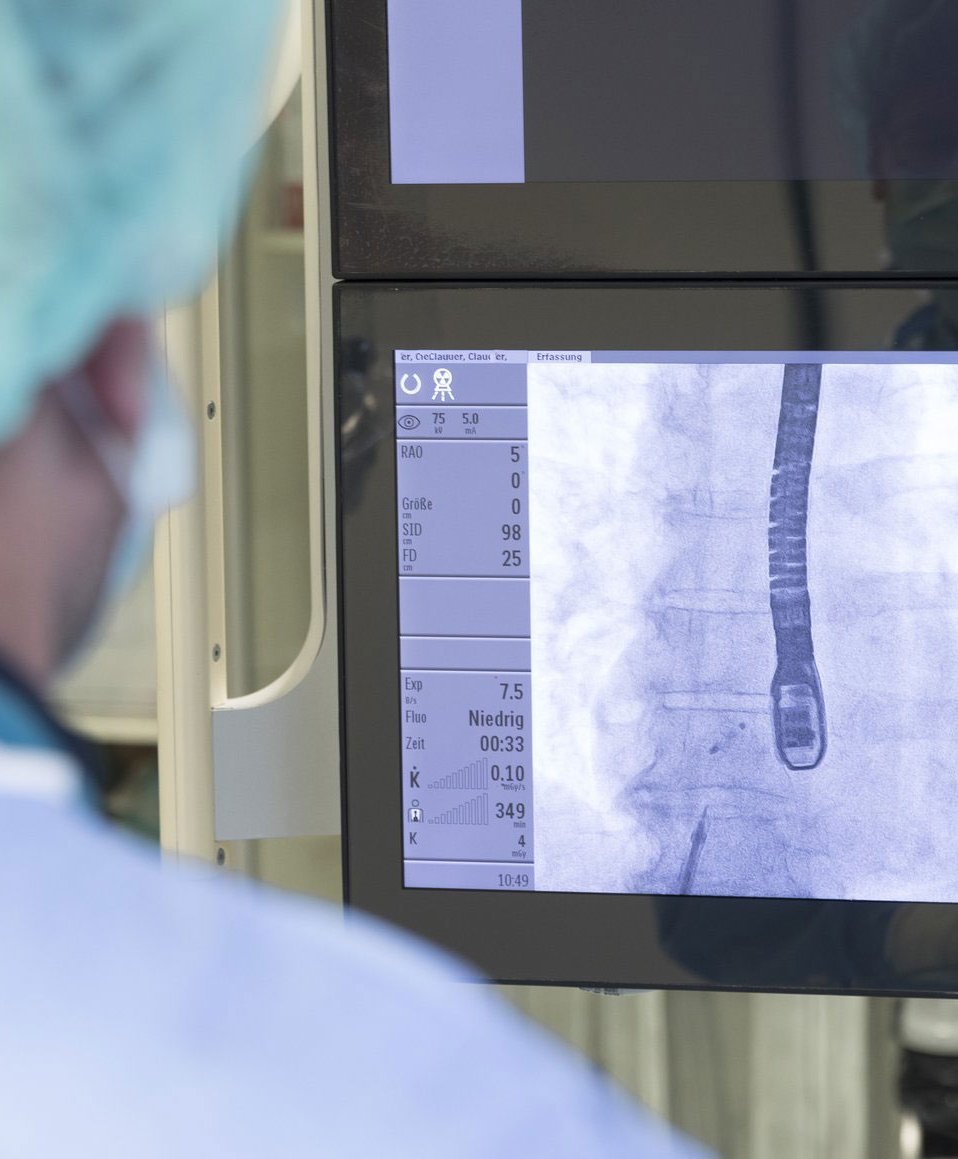 Ein Arzt schaut auf einige Monitore mit Werten und Aufnahmen des Herzens.