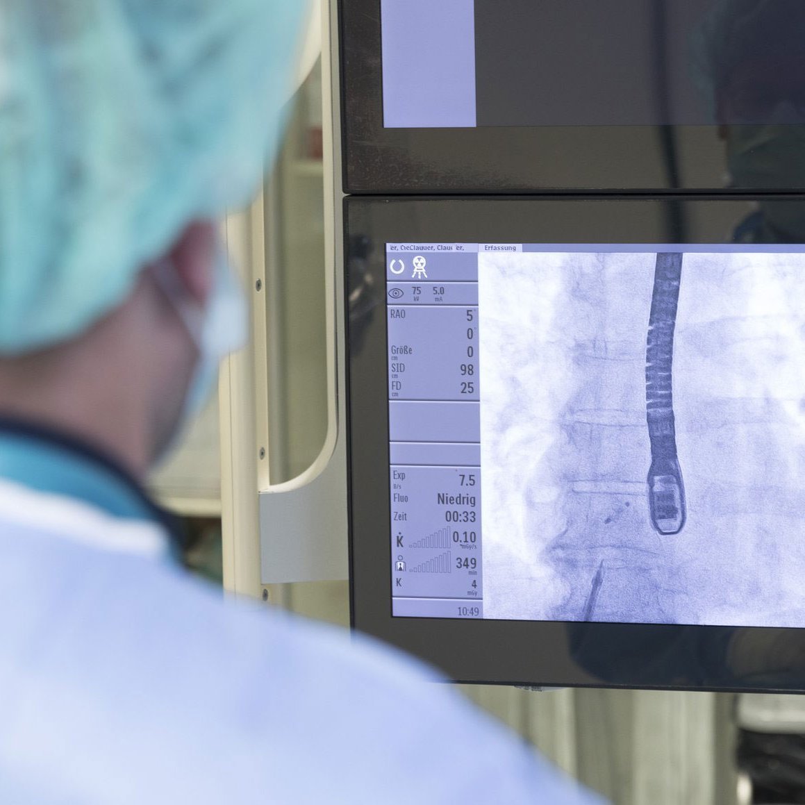 Ein Arzt schaut auf einige Monitore mit Werten und Aufnahmen des Herzens.