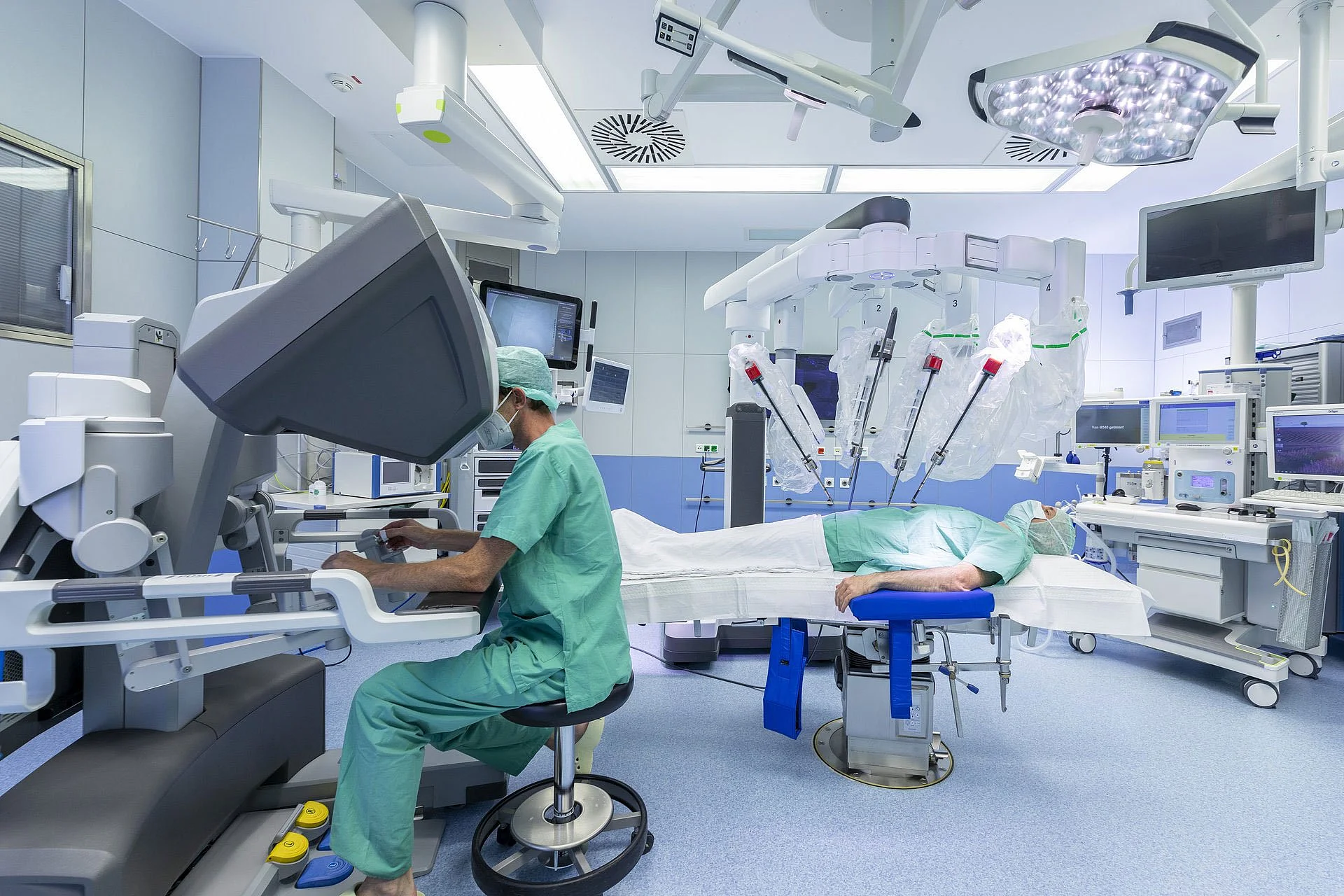 Hightech-OP-Saal im AKH Celle mit chirurgischem Assistenzsystem, Arzt am Steuerungspult und robotergestützter Operationstechnik.