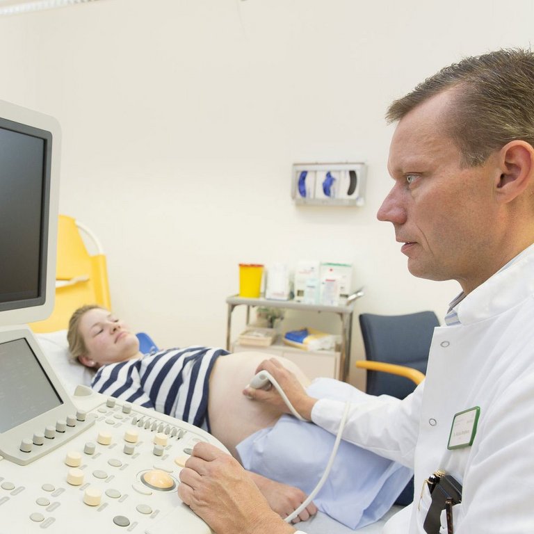 Arzt führt eine Ultraschalluntersuchung bei einer schwangeren Patientin durch.