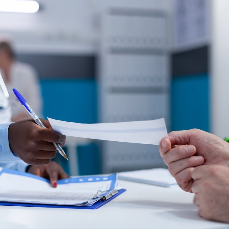 Nahaufnahme eines Klinikspezialisten, der einem älteren Patienten den Analysebericht und das Beratungsergebnis überreicht.