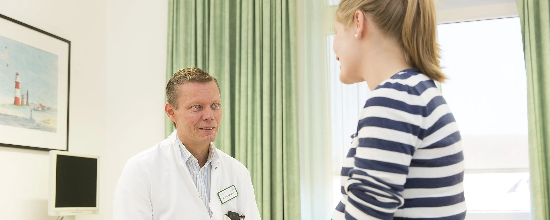 Arzt im Gespräch mit junger Patientin in einer gynäkologischen Sprechstunde.