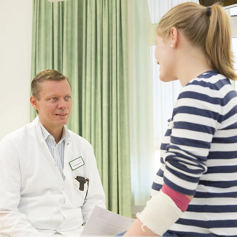 Arzt im Gespräch mit junger Patientin in einer gynäkologischen Sprechstunde.