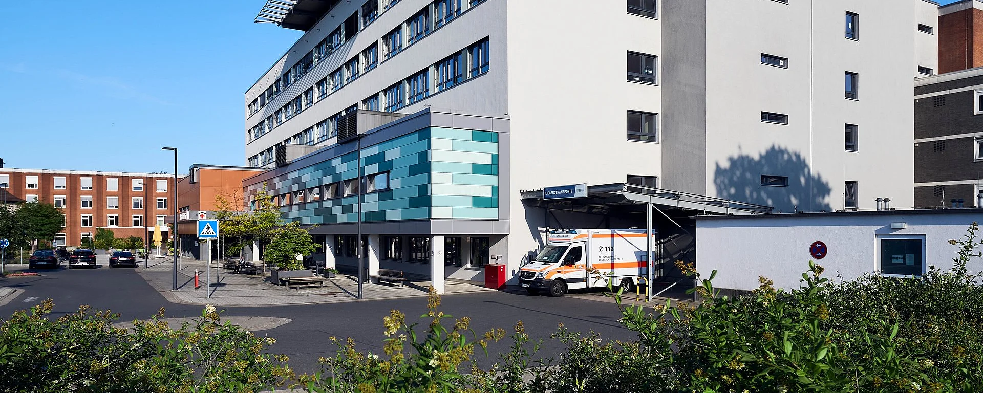 Moderne Krankenhausfassade des Allgemeinen Krankenhauses Celle mit Haupteingang und Fußgängerüberweg.