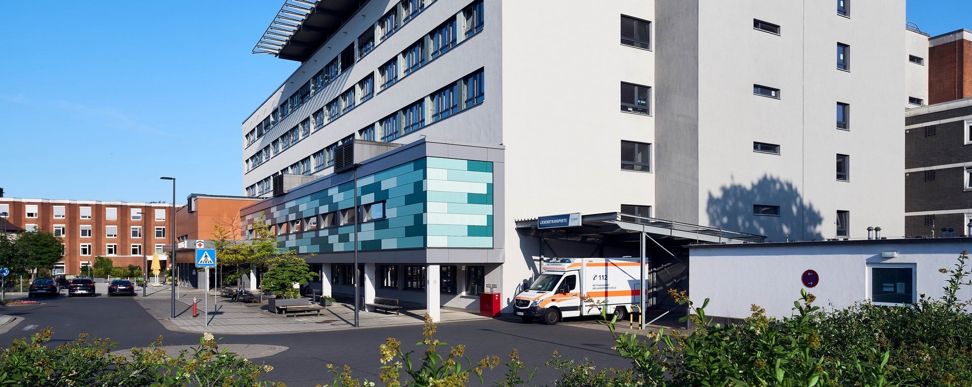 Moderne Krankenhausfassade des Allgemeinen Krankenhauses Celle mit Haupteingang und Fußgängerüberweg.