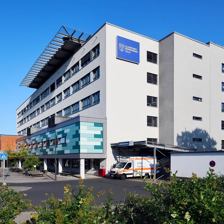 Moderne Krankenhausfassade des Allgemeinen Krankenhauses Celle mit Haupteingang und Fußgängerüberweg.
