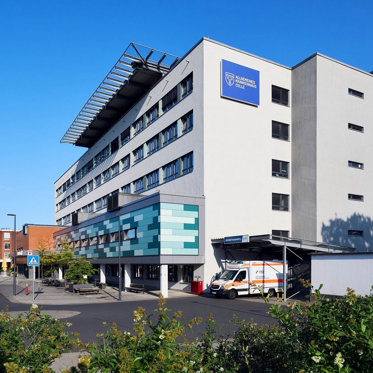 Moderne Krankenhausfassade des Allgemeinen Krankenhauses Celle mit Haupteingang und Fußgängerüberweg.