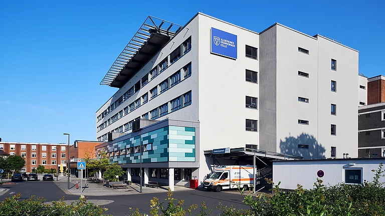 Moderne Krankenhausfassade des Allgemeinen Krankenhauses Celle mit Haupteingang und Fußgängerüberweg.