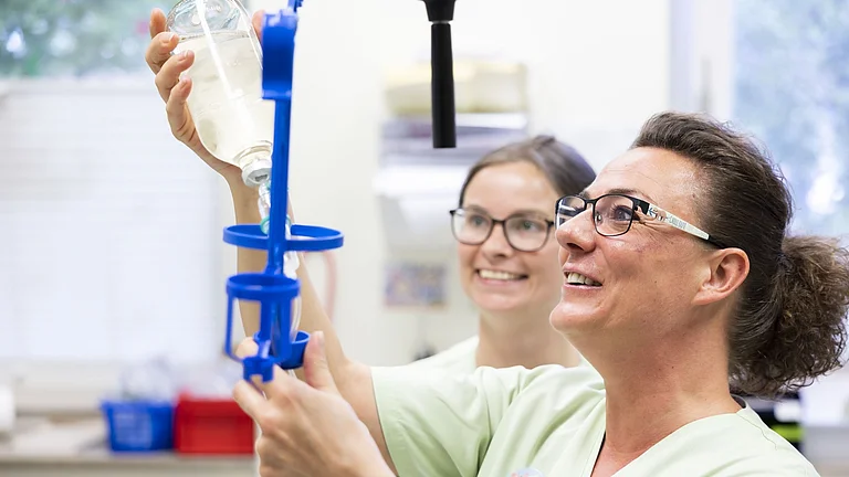 Zwei Pflegekräfte bereiten gemeinsam eine Infusion vor – konzentriert und mit Freude bei der Arbeit.
