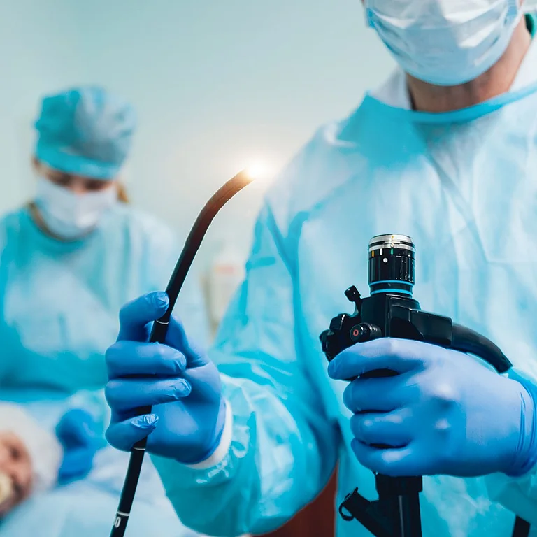 Ein Arzt bereitet ein Endoskop für eine Untersuchung bei einem Patienten im Behandlungszimmer vor.