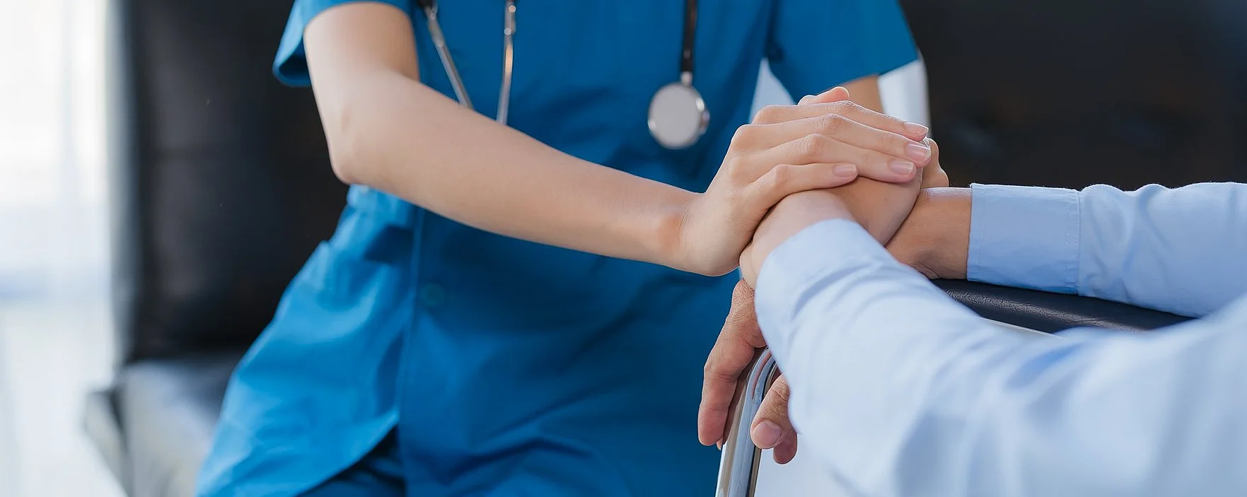 Eine Krankenschwester hält die Hand eines älteren Patienten.