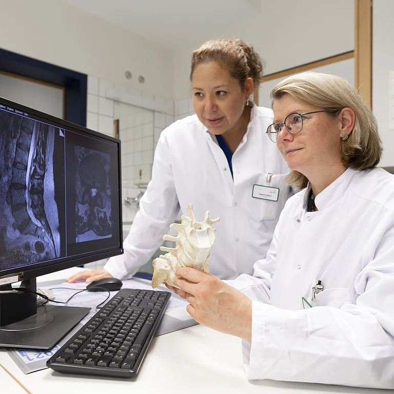 Zwei Ärztinnen betrachten radiologische Aufnahmen am Bildschirm und besprechen die Befunde.