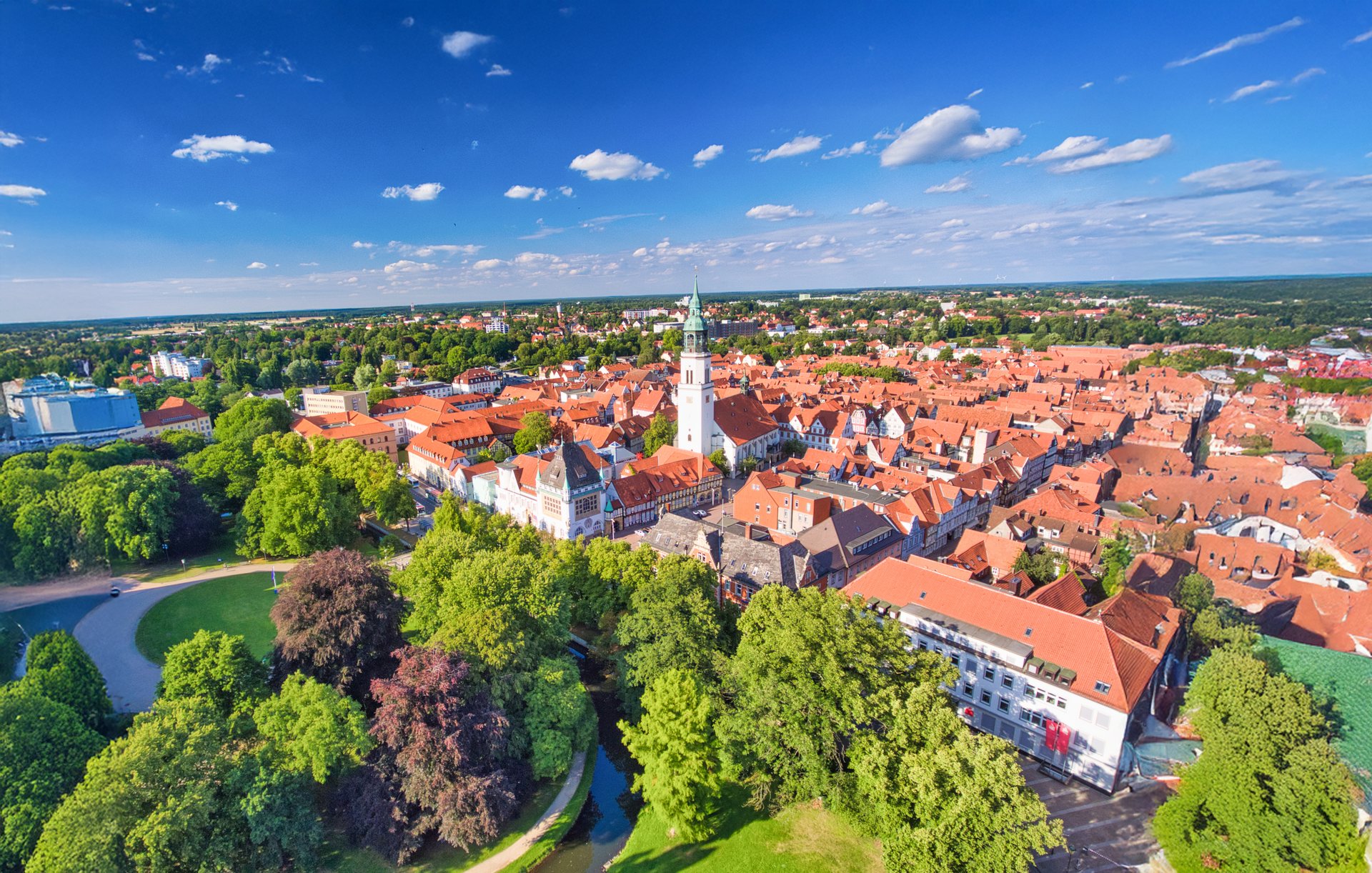 Luftaufnahme der Altstadt von Celle – rote Dächer, grüne Baumkronen und das markante weiße Schloss inmitten historischer Kulisse.