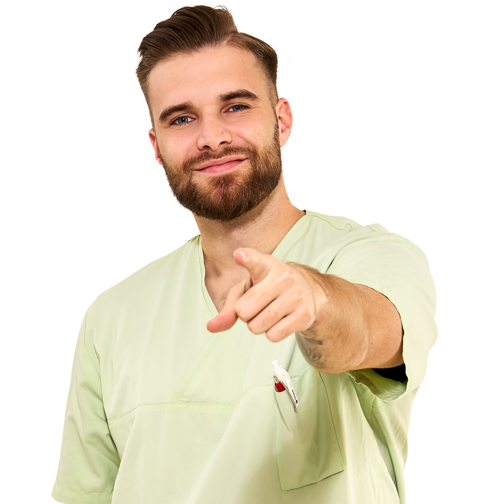 Lächelnder Pfleger in hellgrüner Arbeitskleidung zeigt motiviert nach vorn – ideale Einstiegschance für Pflege-Entdecker, die verschiedene Fachbereiche kennenlernen möchten.