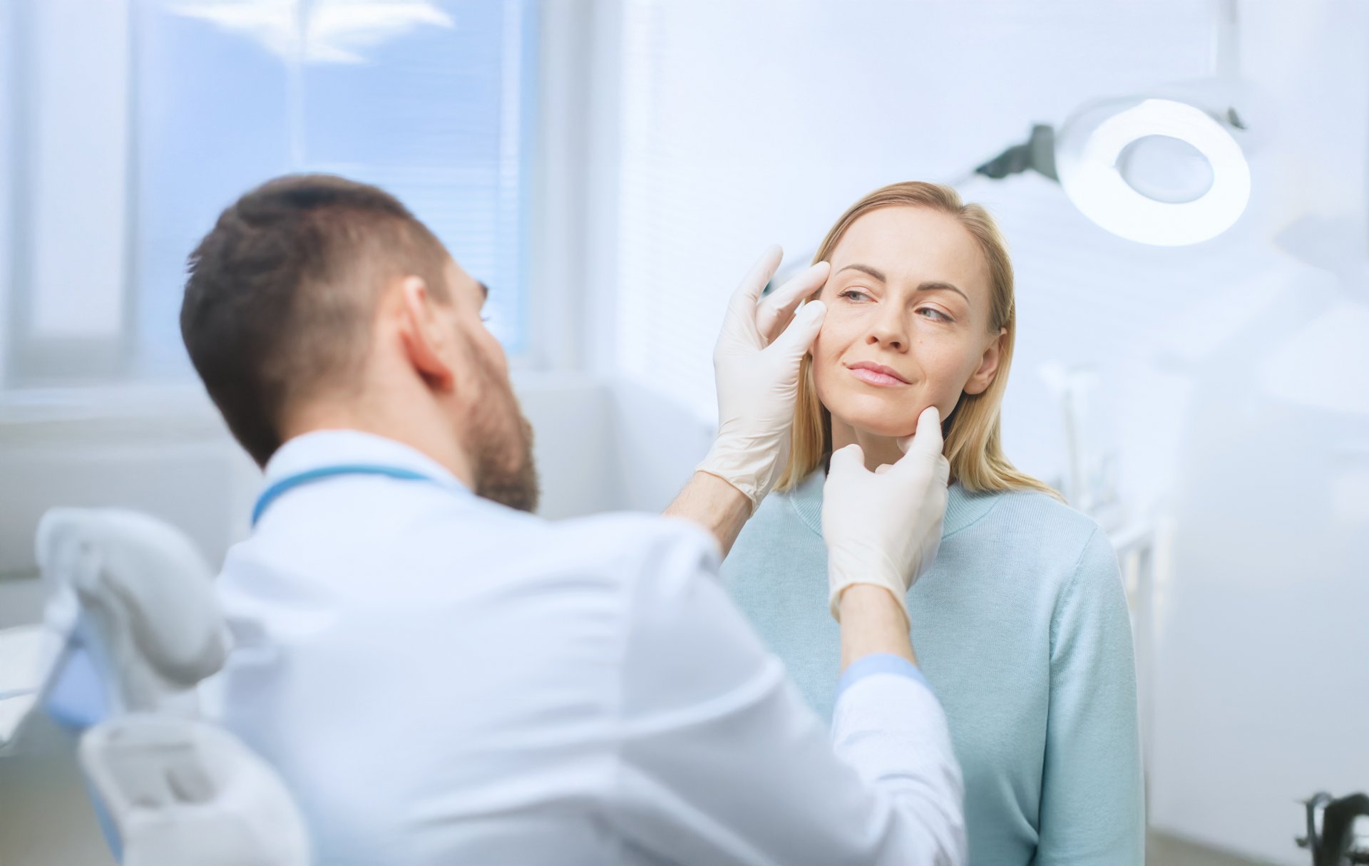 Ein Arzt untersucht das Gesicht einer Patientin – möglicherweise im Rahmen einer ästhetischen oder dermatologischen Behandlung.